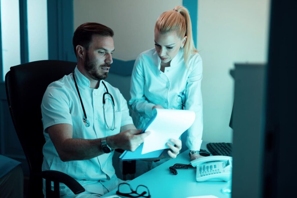 dos medicos cooperando mientras leen documentos medicos paciente hospital